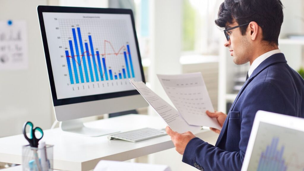 Business professional reviewing financial charts and performance reports on a computer.