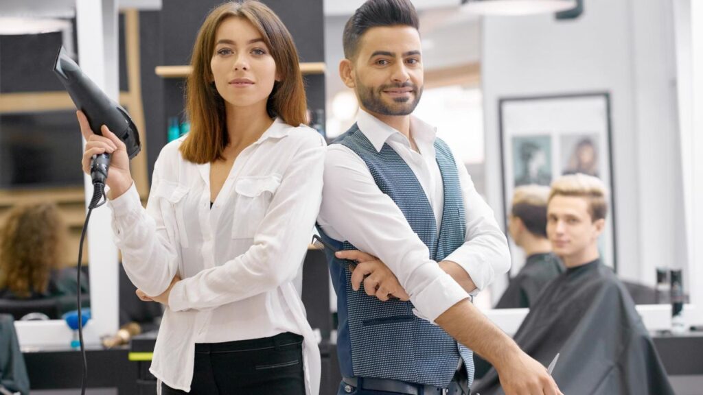 Salon owners standing confidently inside a modern hair salon with professional styling tools.
