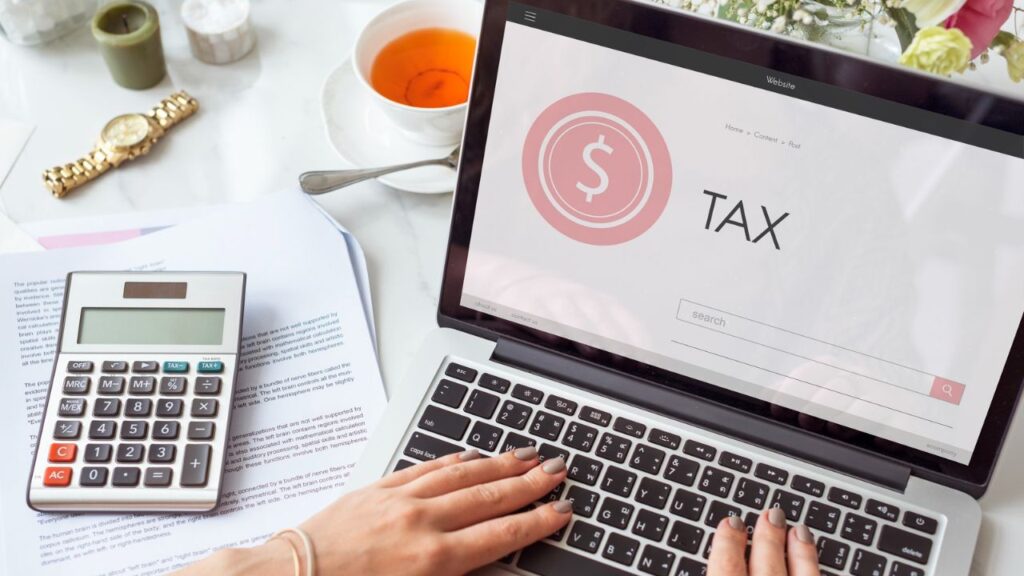 Person using a laptop and calculator to research tax planning strategies for a small business.
