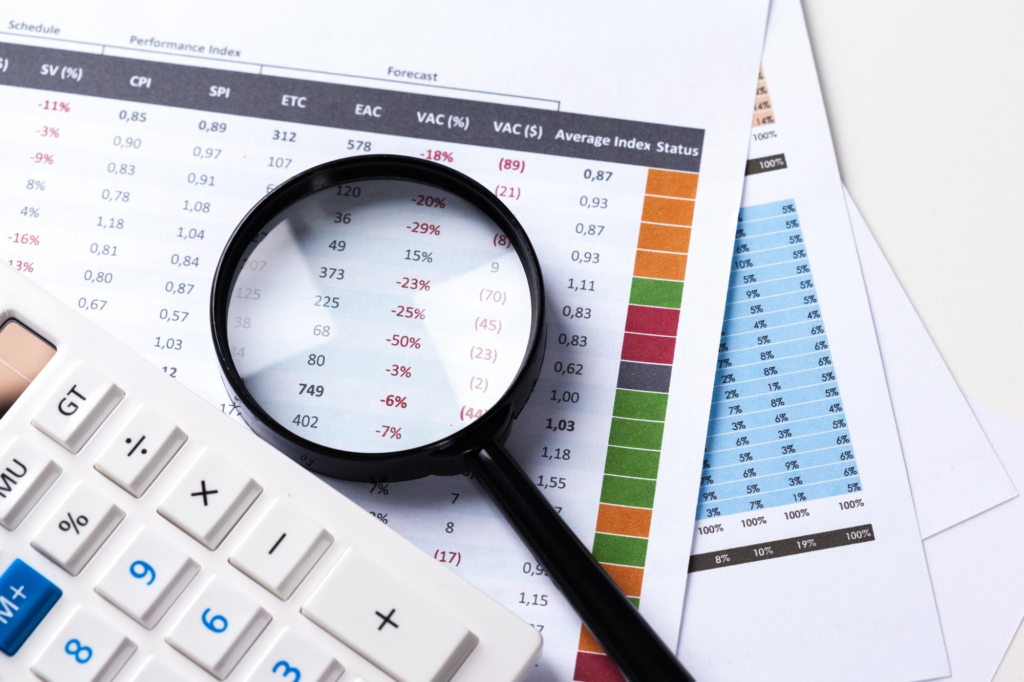 Financial reports, calculator, and magnifying glass used for detailed profit analysis.