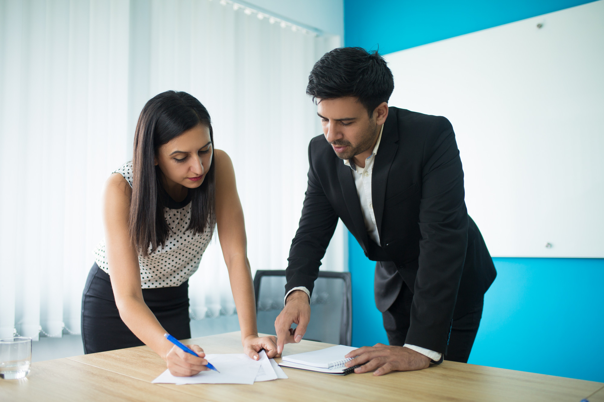 Business professionals reviewing and signing important documents during a planning meeting.