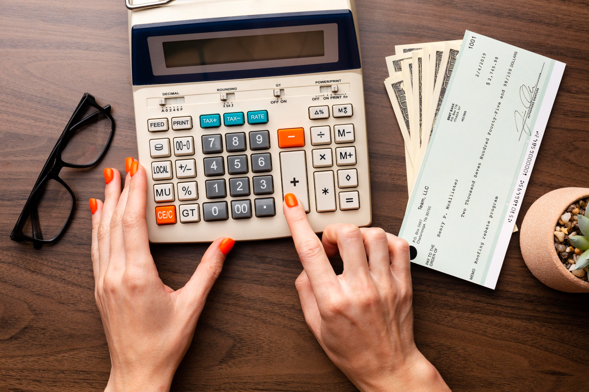  Calculator, paycheck, and cash on a desk illustrating salon business finances and payroll planning.