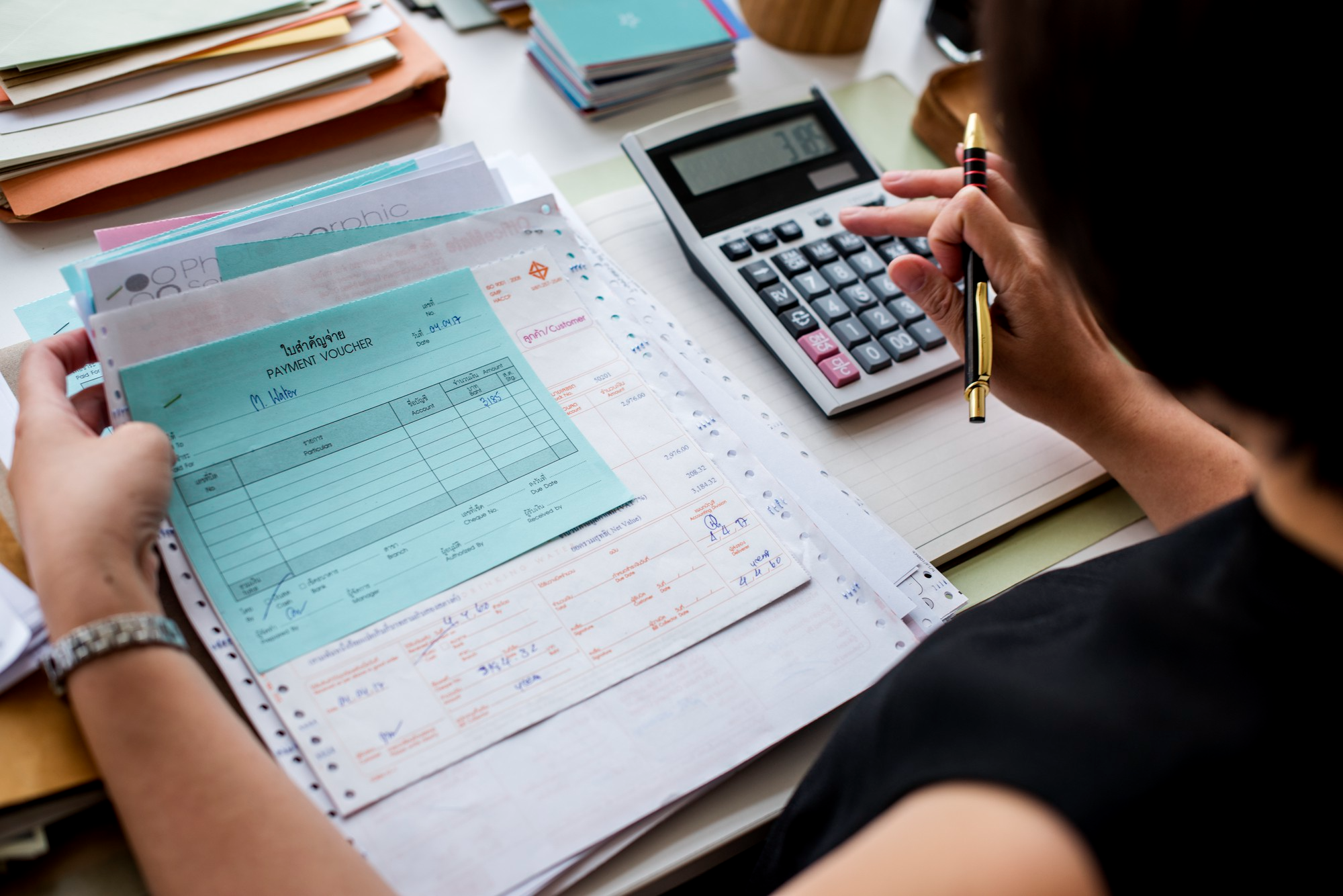 Bookkeeper calculating business expenses and organizing financial records for accurate salon bookkeeping.