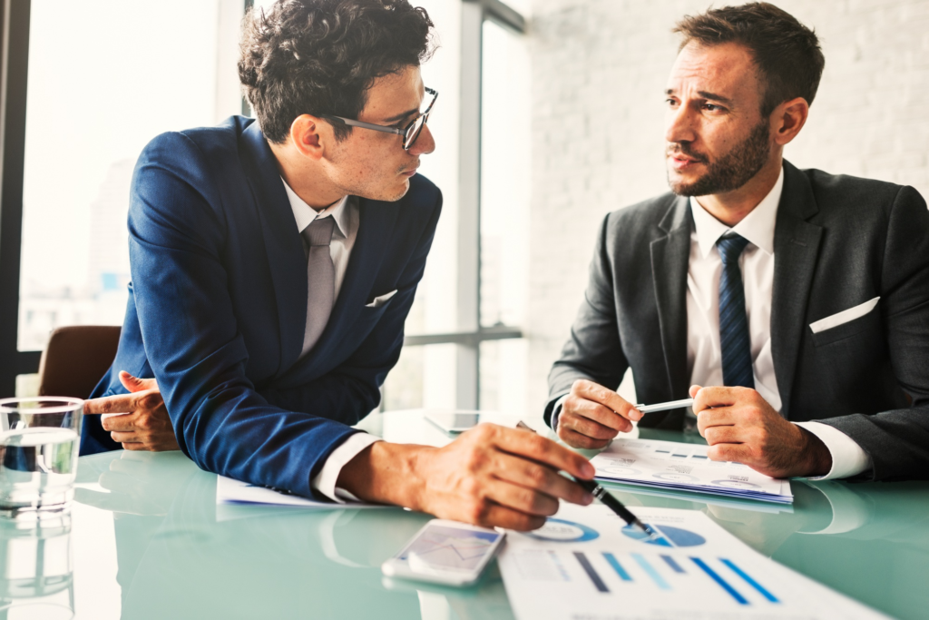Two business professionals reviewing financial reports and discussing business strategy in an office meeting.