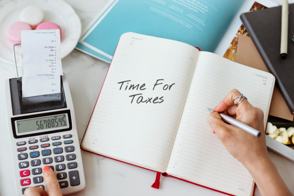 Calculator and planner on a desk with "Time for Taxes" written in a notebook.