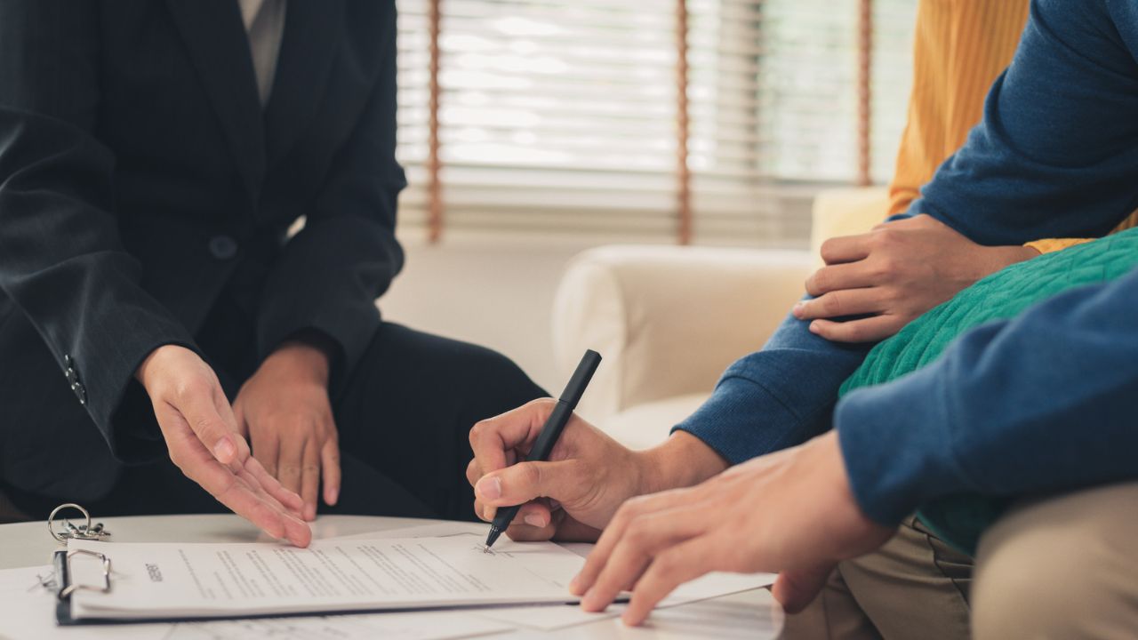 Client signing a business agreement while meeting with a professional consultant.