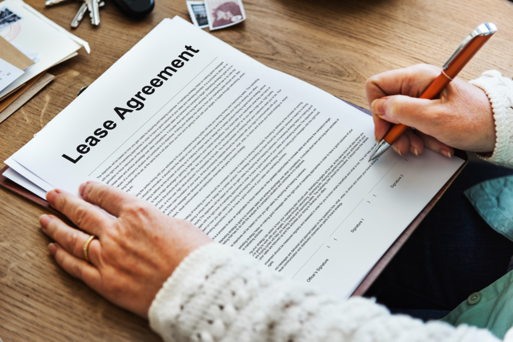Person signing a salon booth rental agreement on a lease document.
