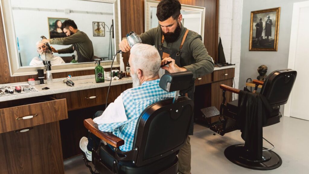 Barber cutting a senior client's hair in a modern salon suite.