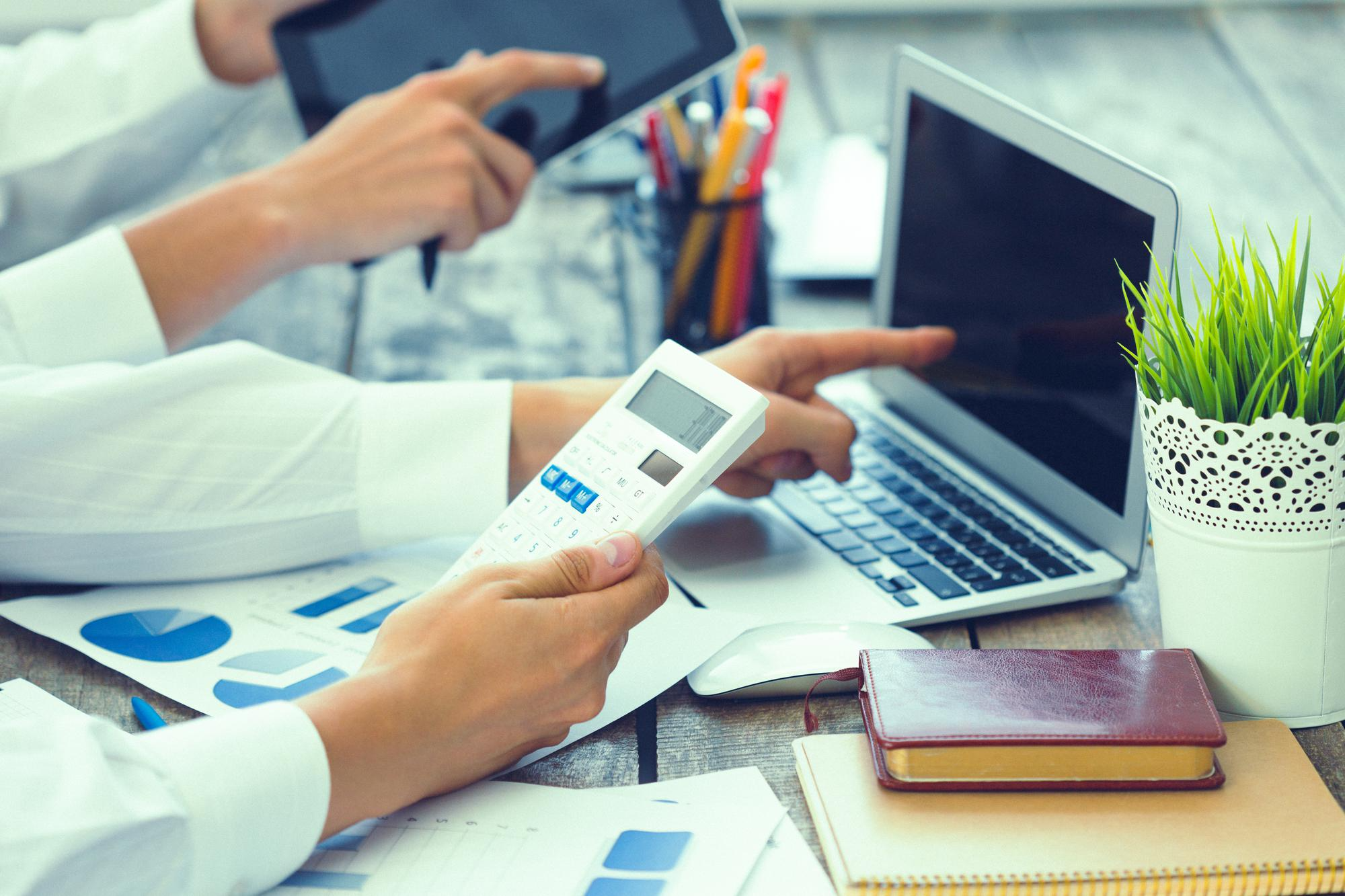 Professionals reviewing financial reports, calculations, and business data using digital tools.