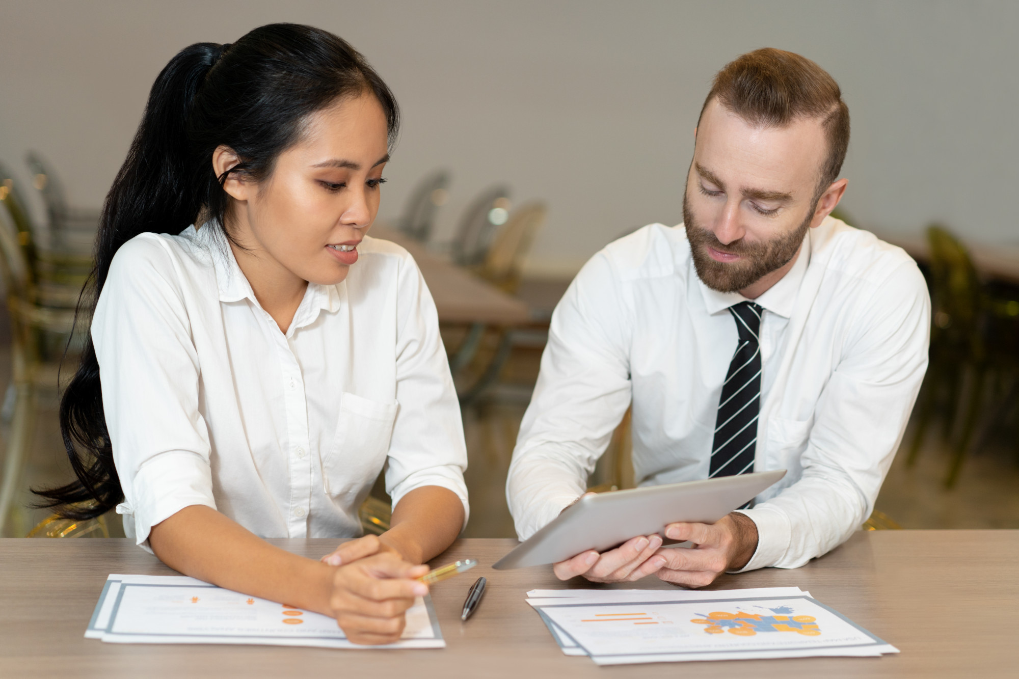 Accounting professionals analyzing financial documents and business data on a tablet during a collaborative finance meeting.